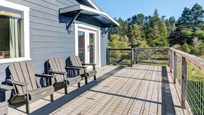 Una terrazza con poltrone Adirondack, un parapetto in legno e vista sugli alberi.