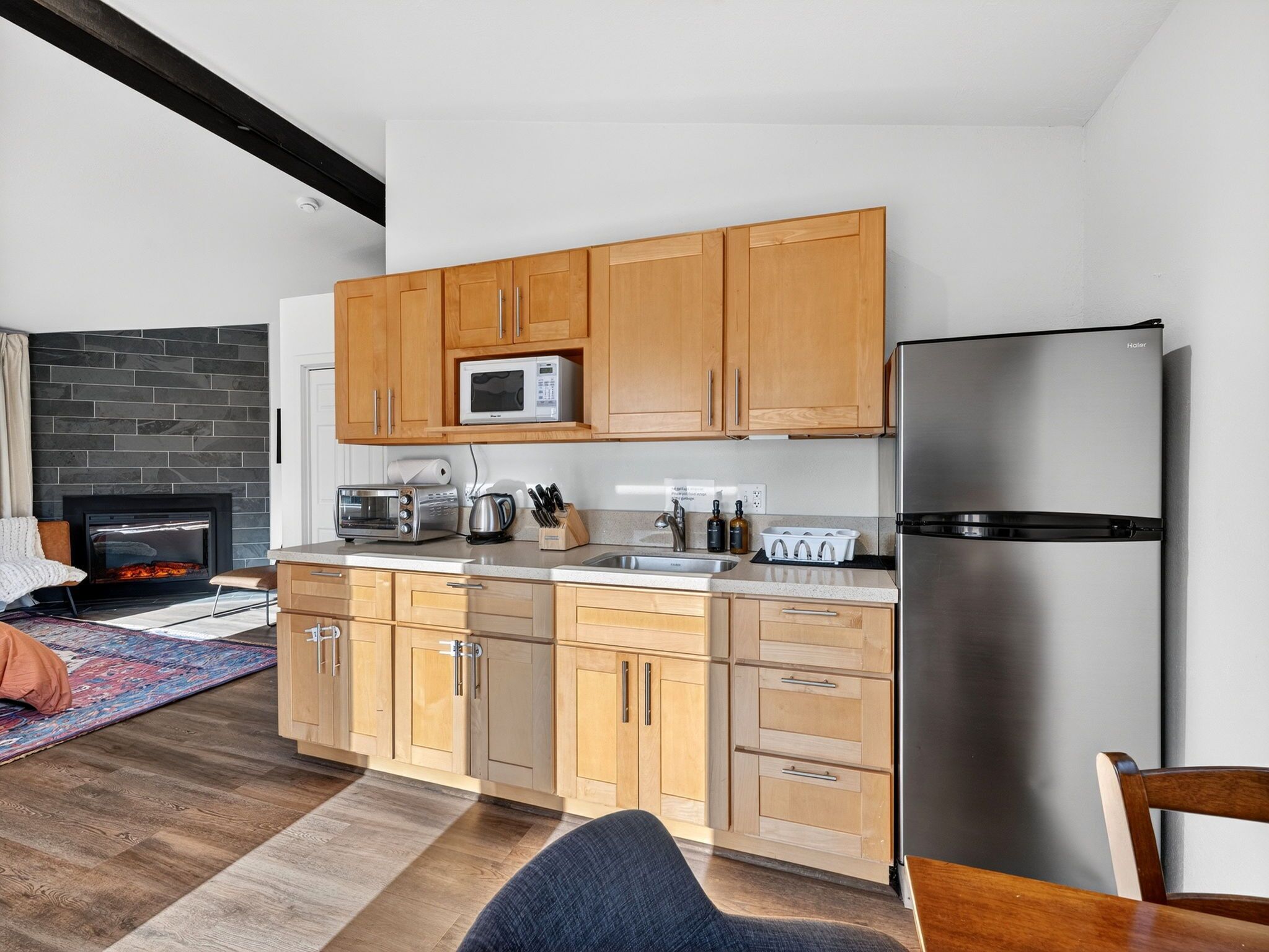 Une cuisine moderne avec des meubles en bois, un réfrigérateur en acier inoxydable, un four à micro-ondes et un four encastré.