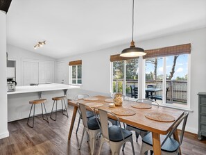 Eine moderne Küche mit einer großen Kochinsel, Barhocker und einem Essbereich mit Holztisch und Stühlen.