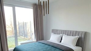 A modern bedroom with a bed, a large window, and a ceiling light fixture.