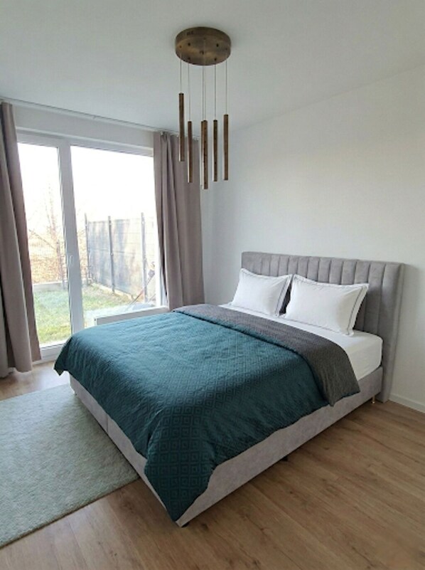 Ein modernes Schlafzimmer mit Bett, großem Fenster und Deckenleuchte.