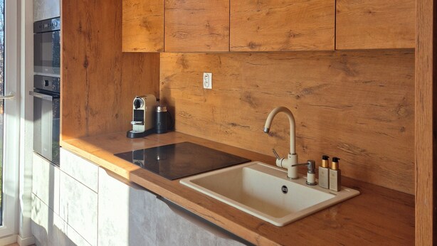 A modern kitchen with a wooden countertop, a built-in sink, and a stainless steel oven.