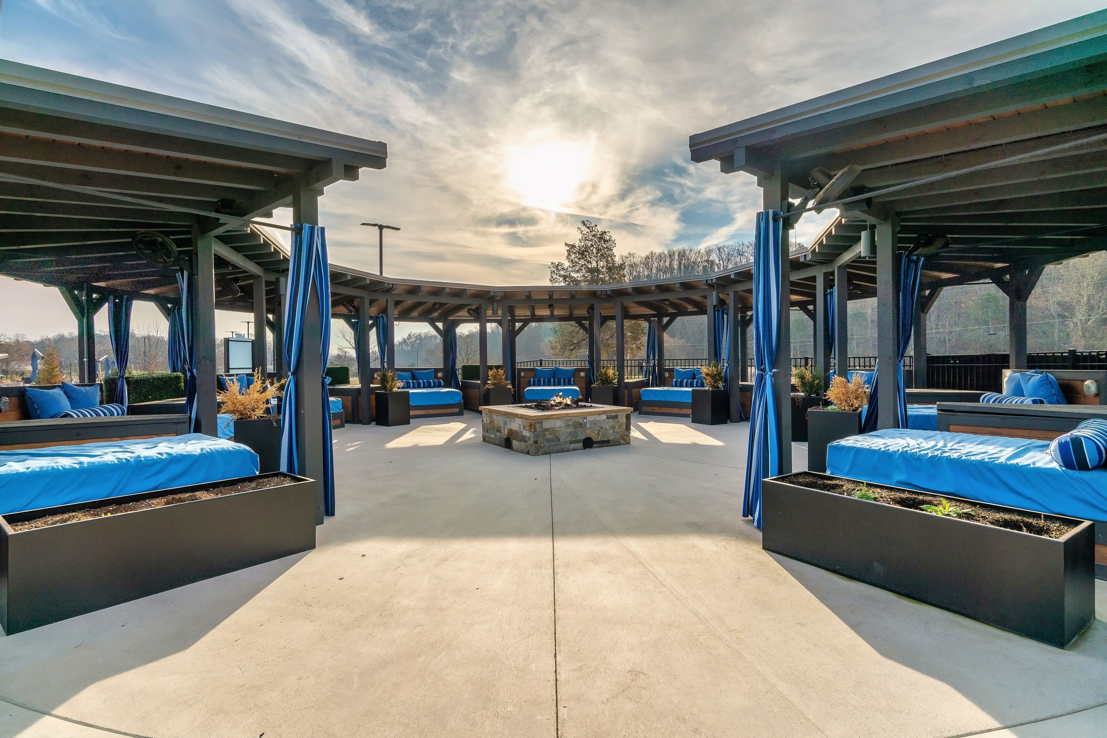 An outdoor seating area with covered benches and a central fire feature.