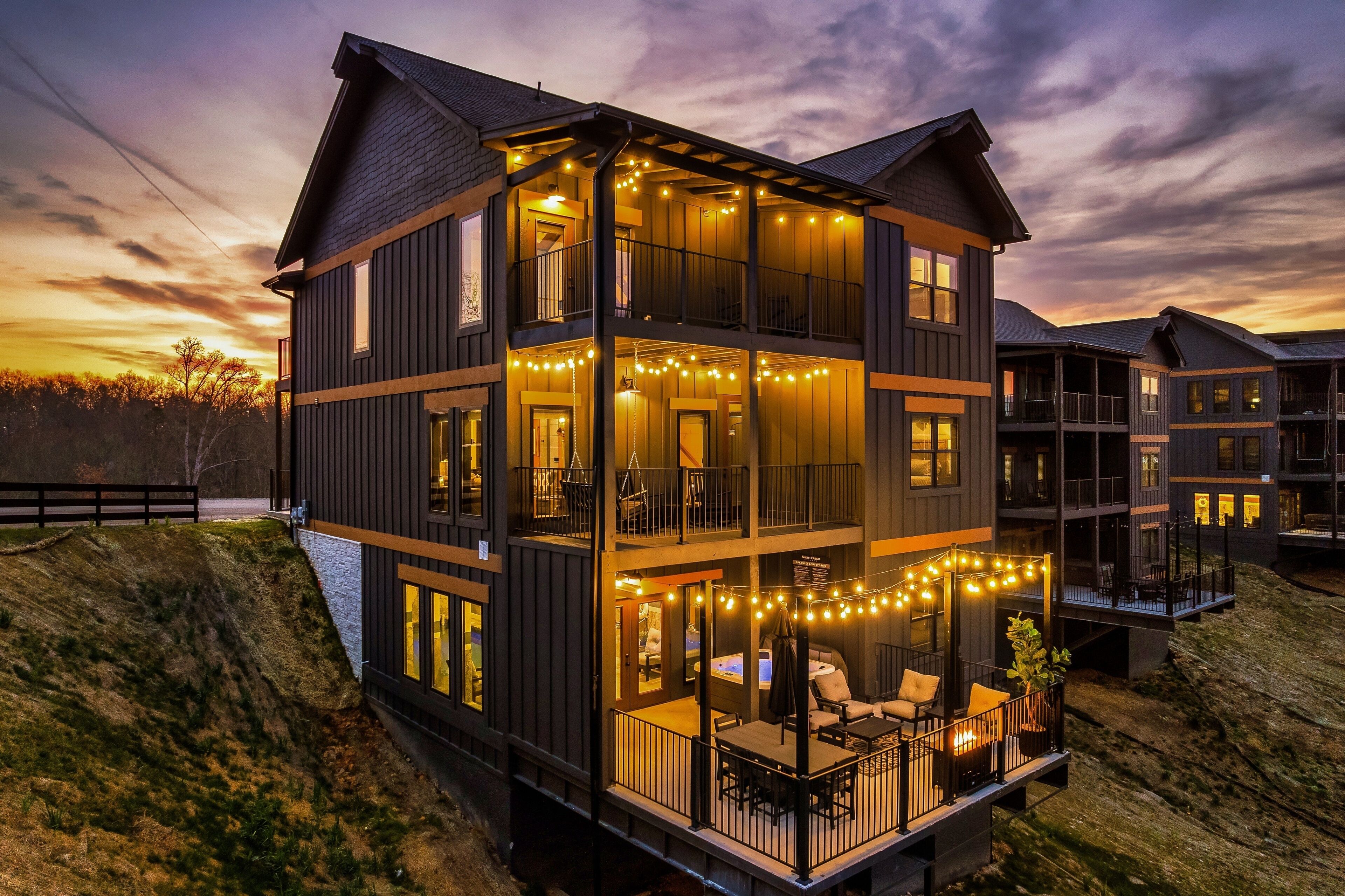 A multi-story building with balconies, string lights, and a view of the surrounding landscape.