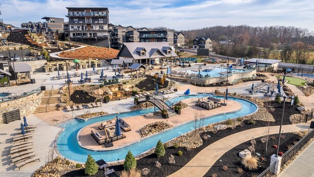 Et resort med en stor swimmingpool, udendørs siddepladser og udsigt over det omkringliggende landskab.