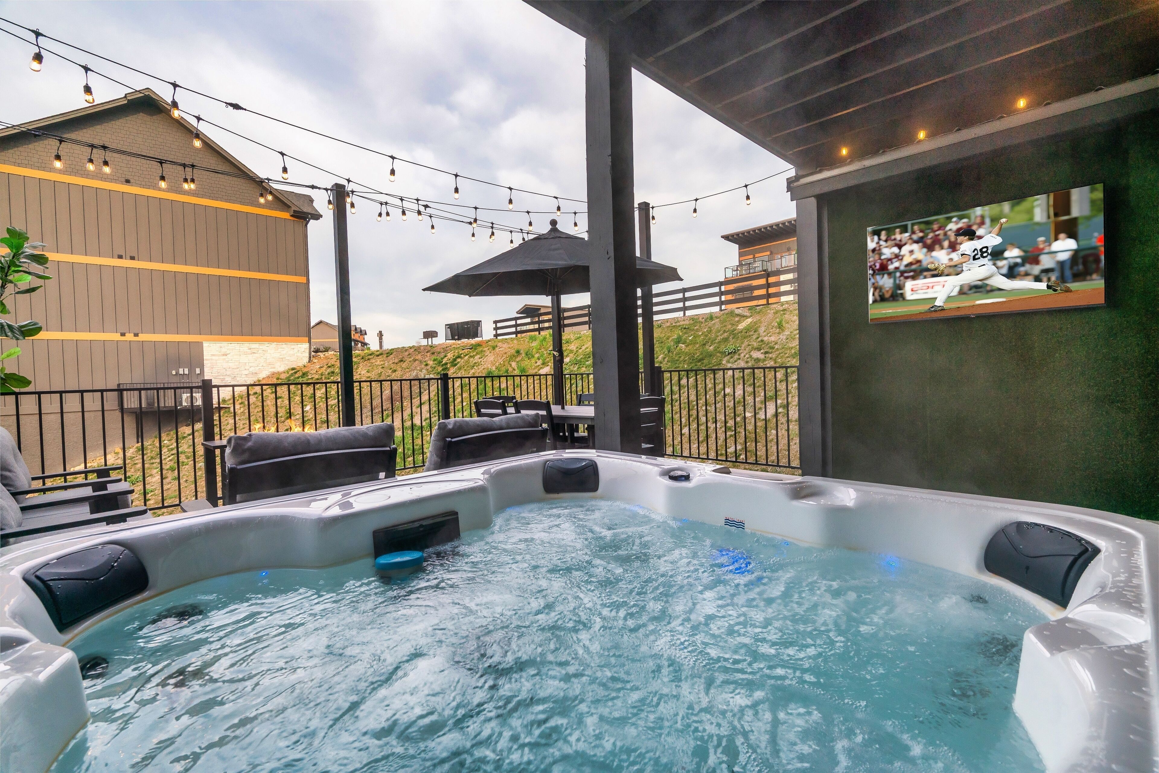 A hot tub with a view of a building and a TV screen displaying a baseball game.