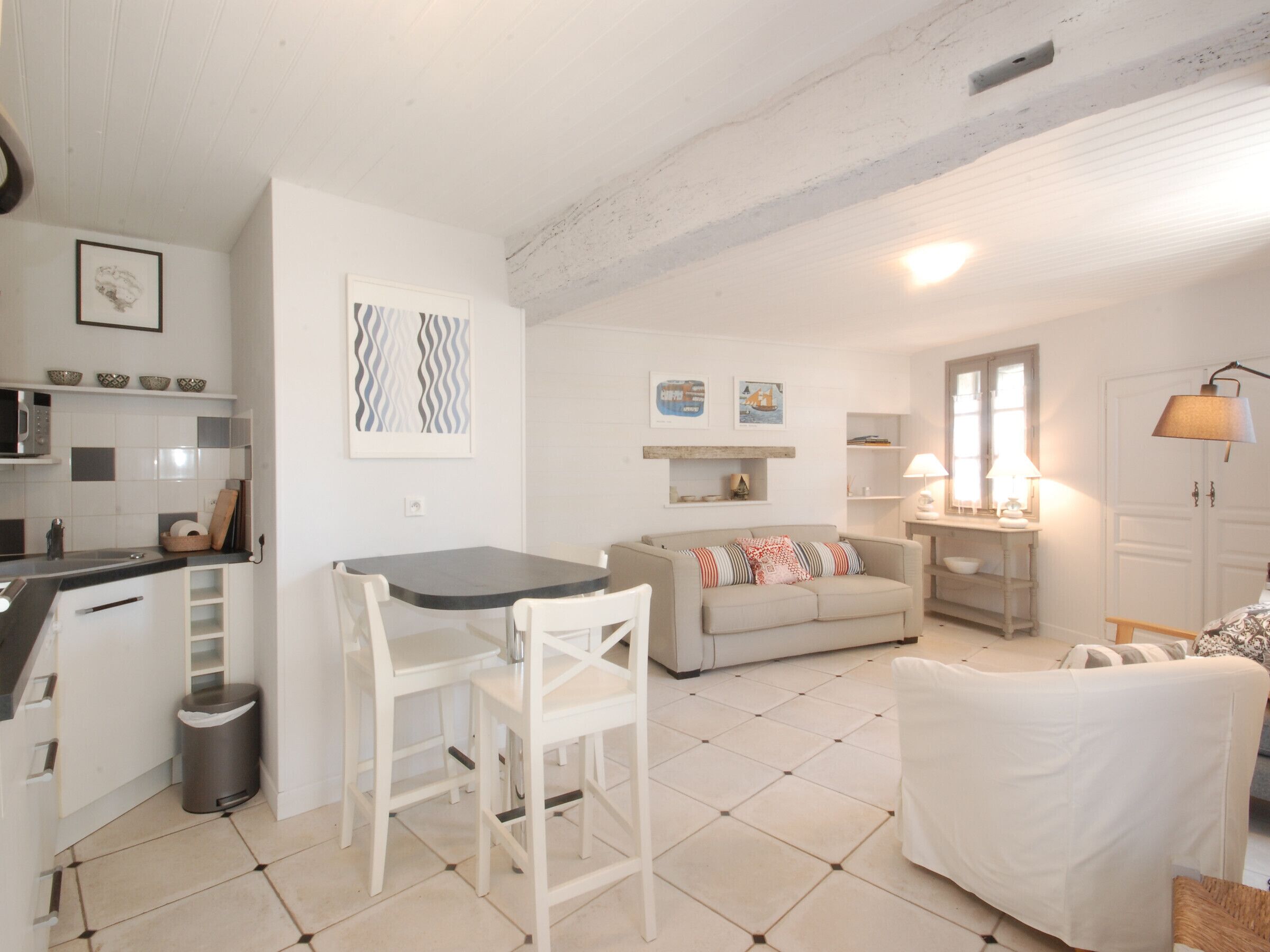 Un espace de vie compact comprenant un coin cuisine, un coin repas et un espace détente avec un canapé et des fauteuils.