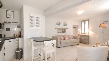 Un espace de vie compact comprenant un coin cuisine, un coin repas et un espace détente avec un canapé et des fauteuils.