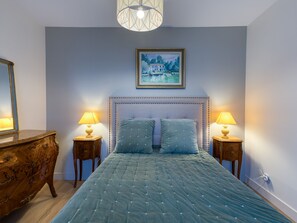 A bedroom with a large bed, two bedside tables with lamps, a dresser, a framed painting on the wall, and a hanging light fixture. - Apartmentby the sea - 4 guests (Châtelaillon-Plage)