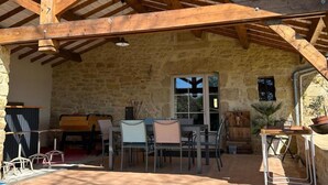 A stone building with a covered patio area, featuring a table and chairs, a piano, and a potted plant. - Charming lodging with AC and parking - 4 guests (Corgnac-sur-l'Isle)