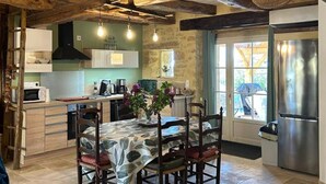 A rustic kitchen with exposed beams, a dining table with chairs, a refrigerator, and a window with a view. - Charming lodging with AC and parking - 4 guests (Corgnac-sur-l'Isle)