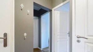 A hallway with a wooden floor, white doors, and decorative wall sconces. - Ground floor apartment, near the sea (Jullouville)