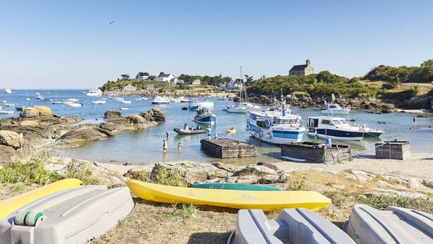 A coastal harbor with boats docked, rocky shore, and a building on a hill. - Ground floor apartment, near the sea (Jullouville)