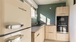 Cocina compacta equipada con refrigerador, estufa, horno microondas y horno.