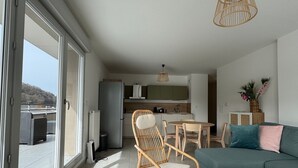 A modern apartment with a dining area, kitchen, and a large sliding glass door leading to an outdoor balcony. - Spacious apartment with large terrace - 4 guests (Aix-les-Bains)
