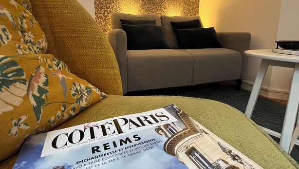 Une pièce avec un canapé, un miroir rond, un magazine et une petite table.