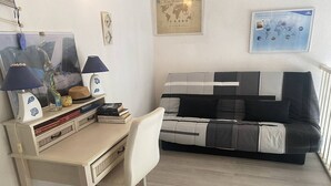 Ett sovrum med en säng, ett skrivbord, en stol, en lampa, en jordglob och en världskarta på väggen.