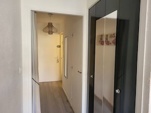 Un corridoio con una porta che conduce a una stanza, un lampadario e una porta con uno specchio e oggetti decorativi.