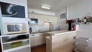 Eine kompakte Küche mit Mikrowelle, Herd, Spüle und einem kleinen Kühlschrank.