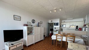 Ein kompakter Wohnbereich mit Fernseher, Schränken, einer Essecke und einer Küchenzeile.