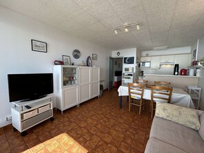 Un espacio habitable compacto con televisión, armarios, zona de comedor y kitchenette.