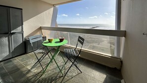 Ein Balkon mit Meerblick, ein Tisch mit Stühlen und ein Fenster mit Jalousien.