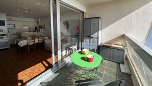 Ein Balkon mit einem grünen Tisch, Stühlen und einem roten Eimer.