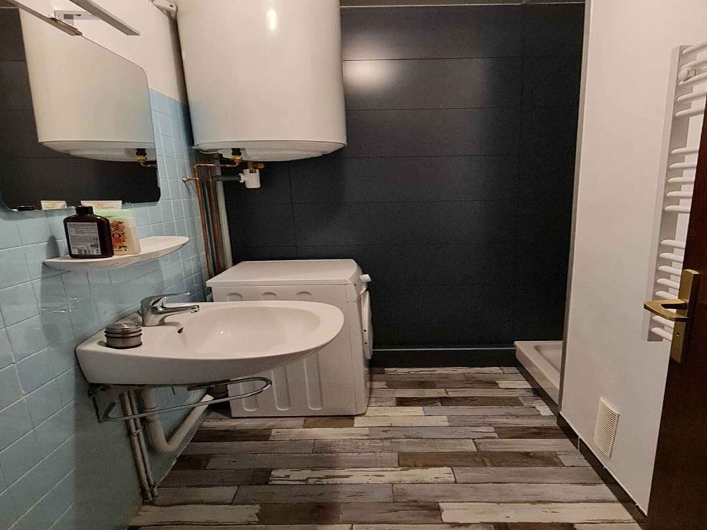 Un baño con lavamanos blanco, inodoro, toallero y zona de ducha.