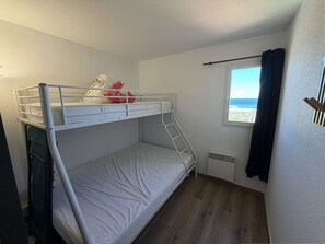 A bunk bed room with a window, a radiator, and a curtain. - Apartment panoramic sea view - 5 guests (Le Barcarès)