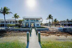 Una propiedad frente al mar con un pasarela de madera que conduce a un edificio de varios pisos con balcones.