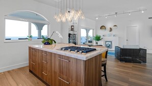 A modern kitchen with a central island, wooden cabinets, and pendant lighting. - Exclusive Oceanfront Luxury Villa in the Keys (Key Largo)