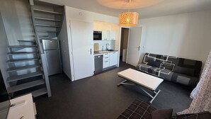 A compact living space with a kitchenette, a sofa, a dining table, and a staircase. - Duplex with sea view, AC - 6 guests (Le Barcarès)