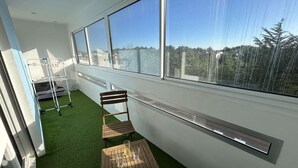 A balcony with a view, a wooden chair, a small table with glasses, and a drying rack. - Modern apartment, dune view - 2 guests (Saint-Hilaire-de-Riez)