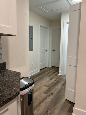 A hallway with wooden flooring, white walls, and a trash can with a recycling symbol. - Lovely 2-bedroom house in St. Augustine perfect for your getaway (St. Augustine)