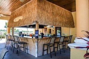 A thatched-roof bar area with bar stools and a counter, likely part of a resort or hotel. - Paradise Home Minutes from Walt Disney  8866 (Kissimmee)