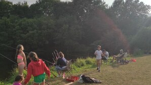 Et udendørs miljø med folk, der dyrker forskellige aktiviteter, herunder et barn med klapvogn, en person i en rød jakke, samt andre siddende eller stående.