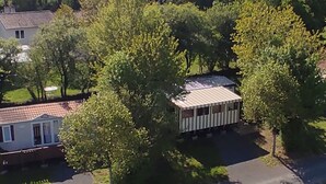 Et boligområde med et lille hus omgivet af træer og en belagt indkørsel.