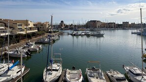 A marina with boats docked, buildings in the background, and a clear sky. - Apartment with port view - 4 guests (Gruissan)