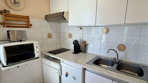 A compact kitchen with a toaster, a coffee maker, a sink, and a microwave. - Apartment with port view - 4 guests (Gruissan)