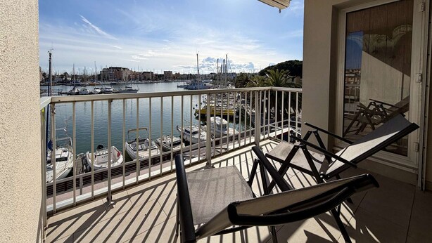 A balcony with a view of a marina, a chair, and a table. - Apartment with port view - 4 guests (Gruissan)