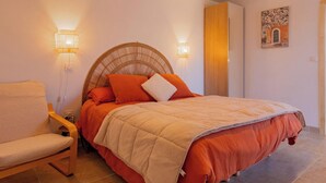 Ein Schlafzimmer mit einem Bett, einem Sessel und zwei Wandleuchten.