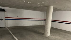 En tom parkeringskælder med hvide vægge, røde og blå striber, og en betondgulv.