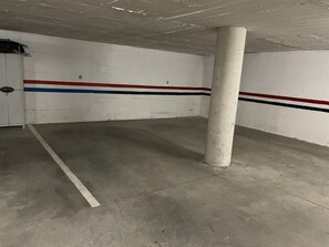 Eine leere Parkgarage mit weißen Wänden, roten und blauen Streifen sowie einem Betonboden.