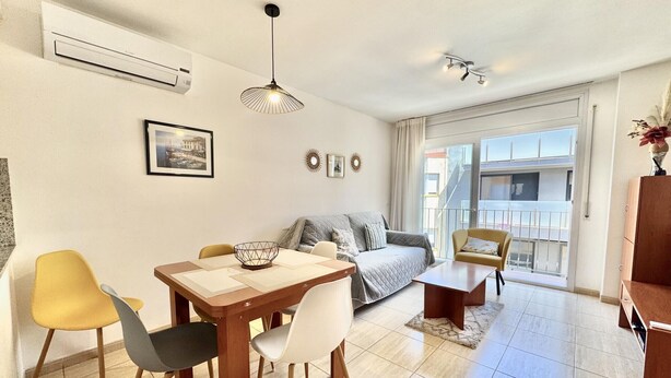 En moderne stue med spisebord, stole, sofa og en balkon med udsigt.