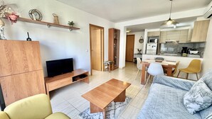 En moderne stue med tv, sofa, sofabord og spiseplads.