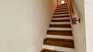 Una scala con gradini in legno e una ringhiera, che porta a una porta con una luce sopra.
