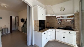 Una cucina con mobili bianchi, una sveglia e un fornello.