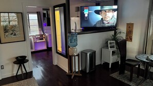A living room with a television, a water dispenser, a small table, and a chair.