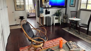 A living room with a television, a dining area, and a kitchen visible through an open doorway.