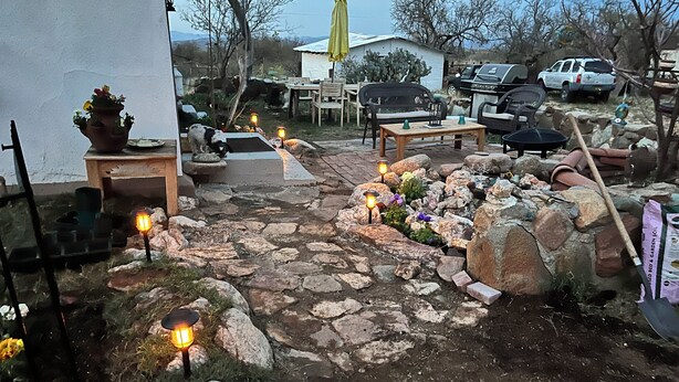 A stone pathway leading to a patio area with outdoor furniture and potted plants.
